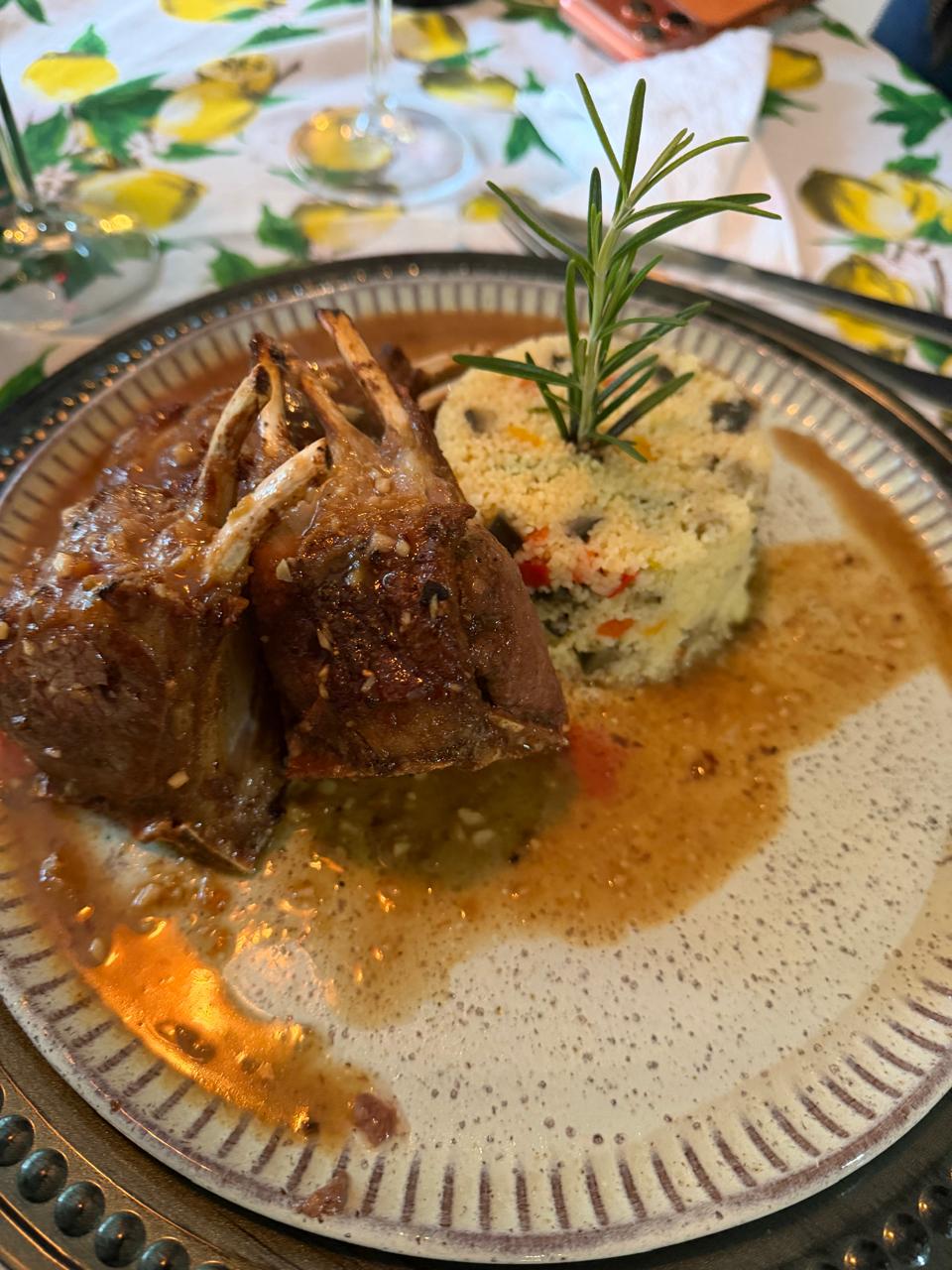 Prato de carne com molho, acompanhamento e ramo de alecrim no Bistrô & Empório do Sabor.