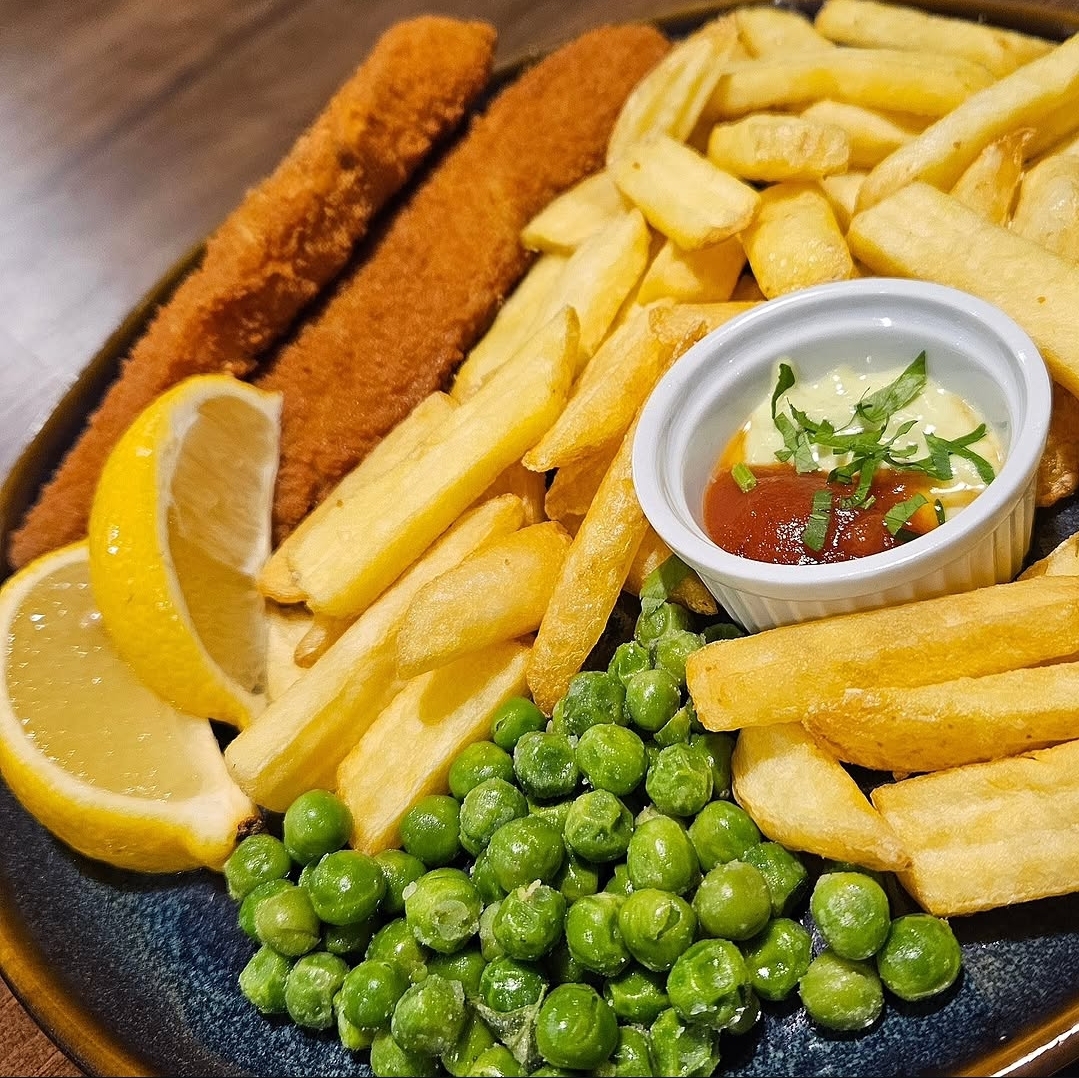 Prato com empanados, batatas fritas, ervilhas, limão e molho na Casa da UNIKA, em Taquaras.