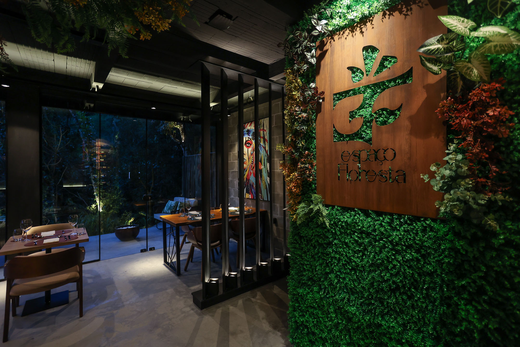 Interior do restaurante com placa Espaço Floresta e parede verde.