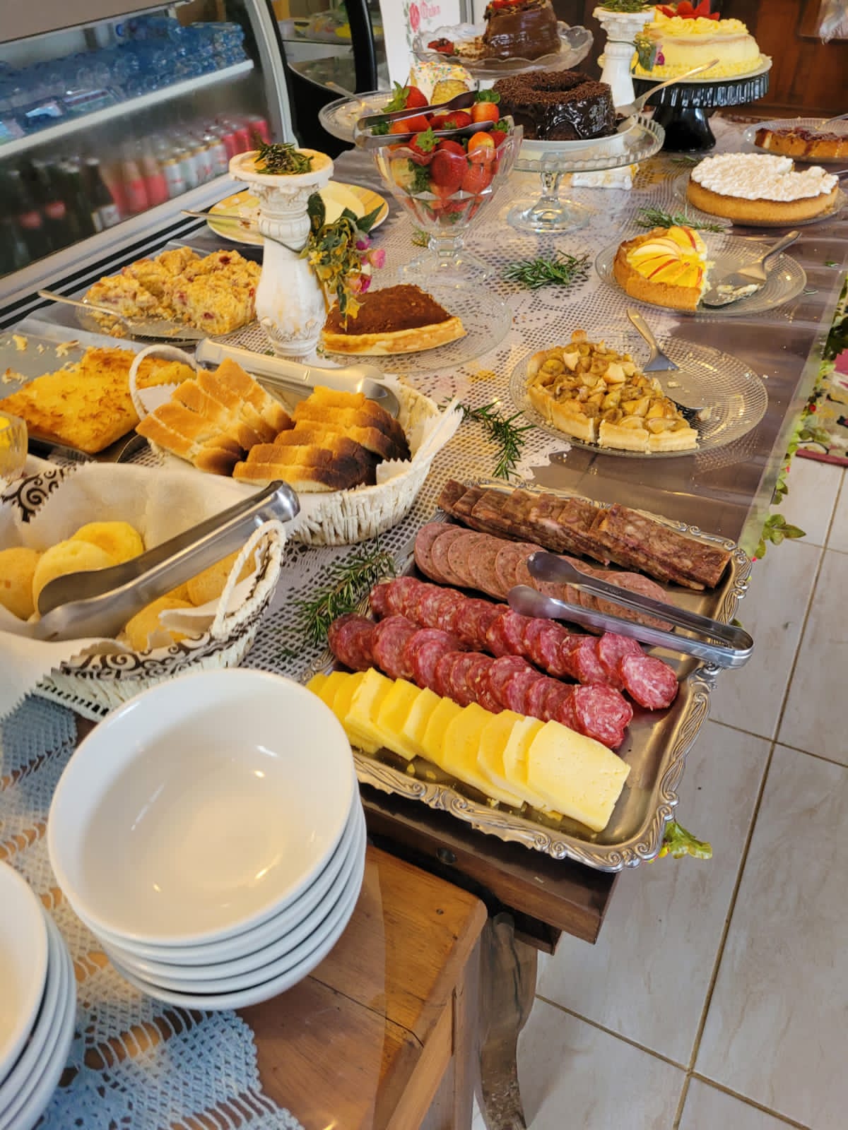 Mesa de café colonial do Käufer, com bolos, tortas, morangos, pães e frios · imagem de acervo.