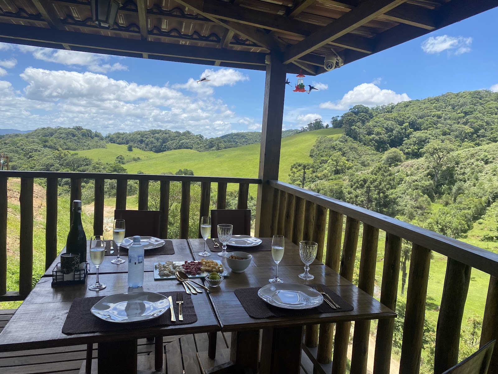 Mesa posta na varanda da Osteria Villa Marini, com vista para campos e morros · imagem de acervo.