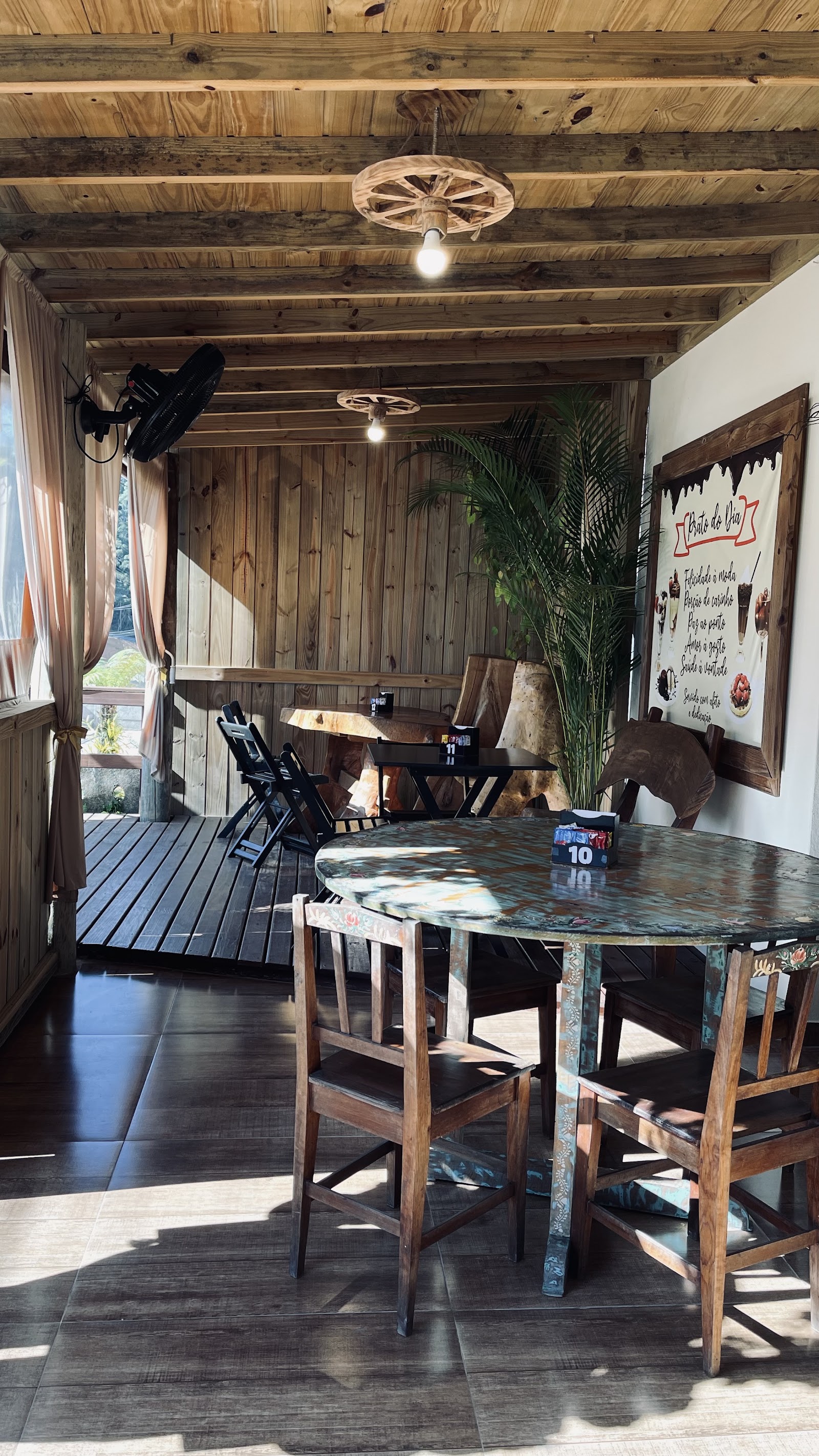Ambiente interno do Sonho Doce Garden Café, com mesas, cadeiras e acabamento em madeira.
